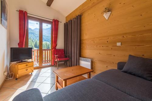 a living room with a couch and a television at Fleurs et Neige in Lanslevillard