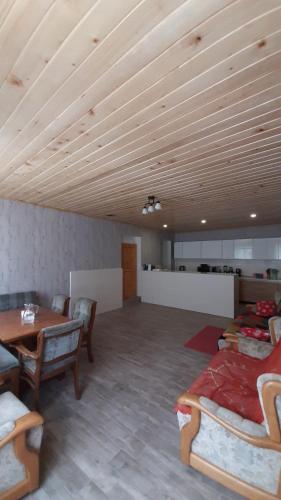 a living room with a wooden ceiling and a table and chairs at Guest house-Lile in Mestia