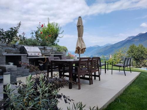 a patio with a table and chairs and an umbrella at Ales Green in Camorino