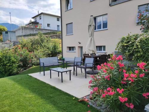 a patio with chairs and a table and a umbrella at Ales Green in Camorino