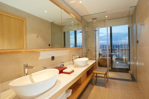 a bathroom with two sinks and a large mirror at Da Nang - Mikazuki Japanese Resorts & Spa in Da Nang