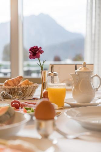 een tafel met ontbijtproducten en een kan sinaasappelsap bij Schüle's Wellnessresort & SPA Adults Only in Oberstdorf