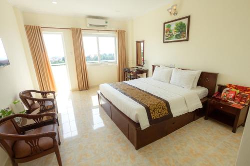 1 Schlafzimmer mit einem großen Bett und 2 Stühlen in der Unterkunft Biet Dien Hotel in Buon Ma Thuot
