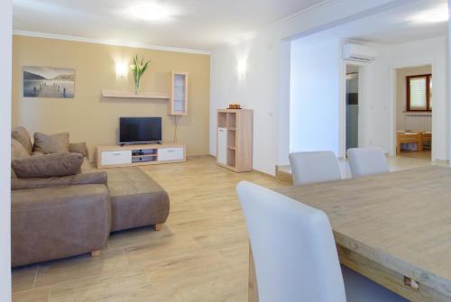 a living room with a table and a couch and a television at Apartments Belvedere in Plovanija