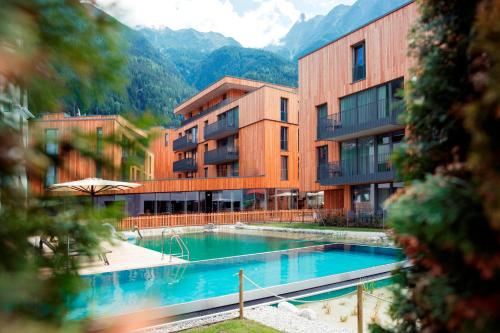 a hotel with a swimming pool in front of some buildings at All-Suite Resort Ötztal in Oetz