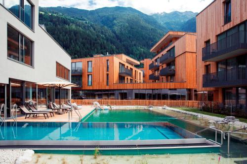 a hotel with a swimming pool in front of two buildings at All-Suite Resort Ötztal in Oetz