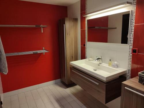 a bathroom with a white sink and a red wall at Grand T2 lumineux Viarme/Talensac avec parking in Nantes