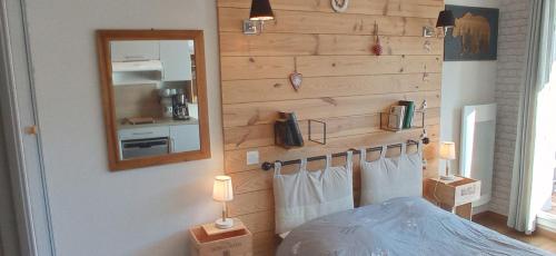 1 dormitorio con pared de madera, cama y espejo en studio Loubat pyrénée, ménage inclus, en Arette