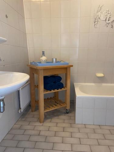 een badkamer met een tafel, een wastafel en een bad bij Atlantis Appartement in Egmond aan Zee