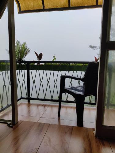 a chair sitting on a balcony looking out at the water at Raymond's Holiday Homes in Vythiri