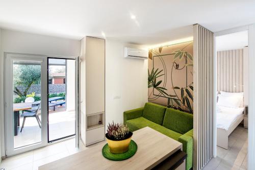 un soggiorno con divano verde e tavolo di GOLDIMARE GARDEN RESIDENCE a Umag (Umago)