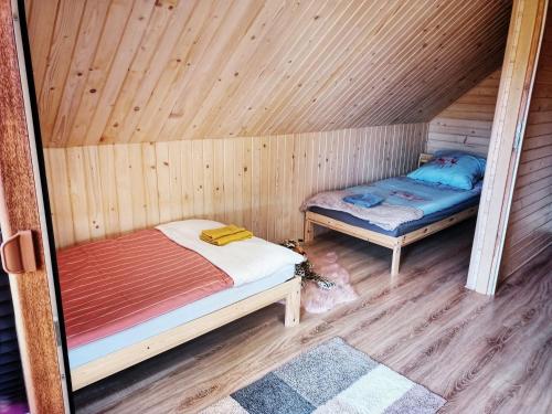 a room with two beds in a wooden cabin at Alma in Rzyki