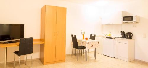 une cuisine avec une table, des chaises et une table ainsi qu'une cuisine avec un comptoir dans l'établissement Haus Emona - Ihre Pension in Freiburg, à Fribourg-en-Brisgau