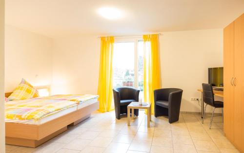 a bedroom with a bed and a desk and chairs at Haus Emona - Ihre Pension in Freiburg in Freiburg im Breisgau