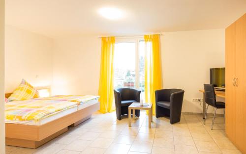 - une chambre avec un lit, un bureau et des chaises dans l'établissement Haus Emona - Ihre Pension in Freiburg, à Fribourg-en-Brisgau