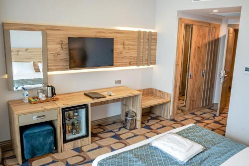 a room with a bed and a desk with a television at BLUE MUDANYA HOTEL in Bursa
