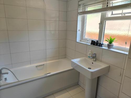 a white bathroom with a sink and a bath tub at Piping Green 5 bedroom House in Winchester