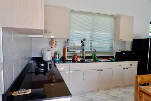 a kitchen with white cabinets and a black counter top at Siri Nathai Pool Villa สิรินาไทย พูลวิลล่า in Krabi town