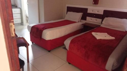 two beds in a hotel room with red and white sheets at Emampingeni lodge in Bizana