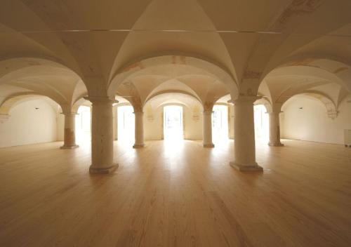 an empty room with columns and a wooden floor at Montebelo Mosteiro de Alcobaça Historic Hotel in Alcobaça