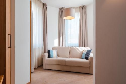 a living room with a white couch in front of a window at Albergo Caffe Centrale in Mezzocorona