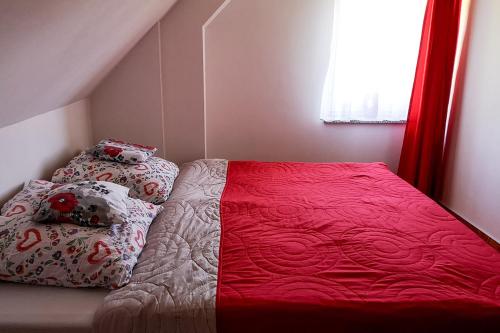 a bed with a red blanket and pillows in a bedroom at Ranczo Spełnionych Marzeń in Sosnówka