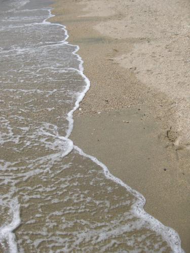 a close up of the sand and water on the beach at Armiriki Rooms in Vrasná
