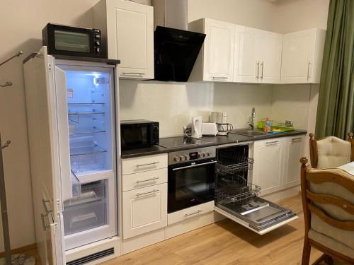 a kitchen with white cabinets and an open refrigerator at Apartment Top Diplomat in Prague