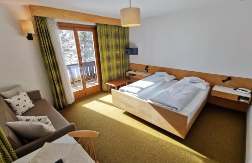 a hotel room with a bed and a couch at Hotel la Plaza in Corvara in Badia