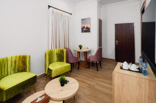 a living room with green chairs and a table at Quest Boutique Hotel in Gwarinpa