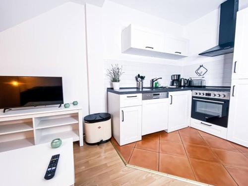 a small kitchen with white cabinets and a television at R&L Apartment Wettiner Strasse in Leipzig
