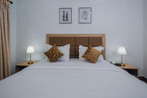 a bedroom with a large white bed with two lamps at Quest Boutique Hotel in Gwarinpa