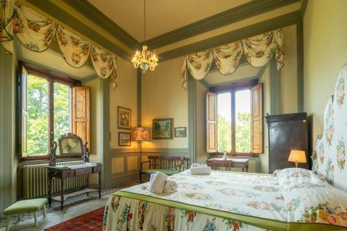 a bedroom with a bed and a desk and windows at Villa Votanidi by VacaVilla in Borgo San Lorenzo