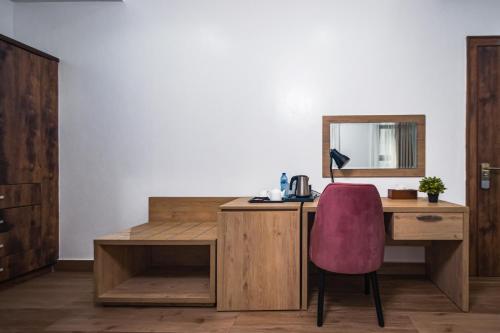 a desk with a pink chair and a mirror at Quest Boutique Hotel in Gwarinpa
