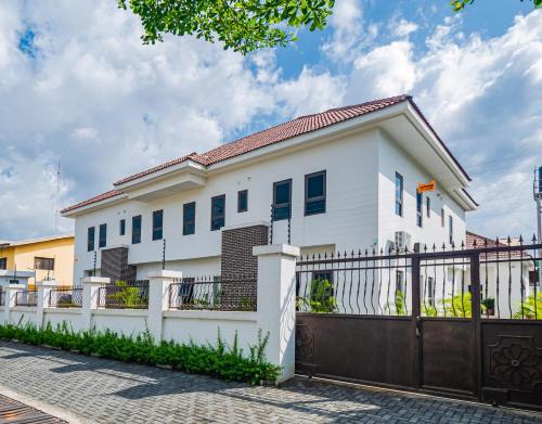 a white house with a gate and a fence at Quest Boutique Hotel in Gwarinpa