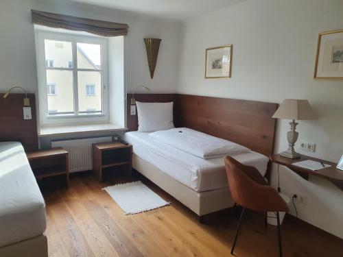 a bedroom with a bed and a desk and a window at Hotel Schierlinger Bräustüberl in Schierling