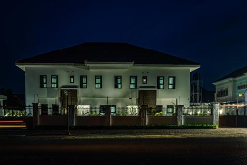 a white house with a fence in front of it at night at Quest Boutique Hotel in Gwarinpa