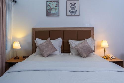 a bedroom with a bed with pillows and two lamps at Quest Boutique Hotel in Gwarinpa