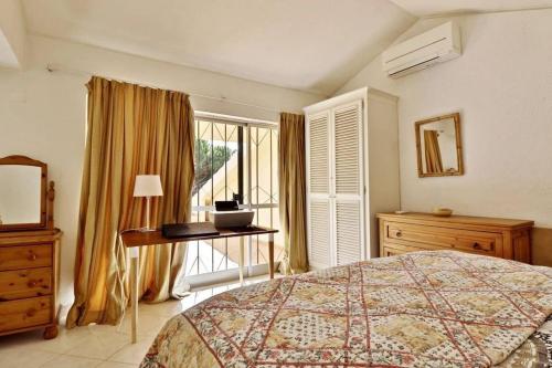 Schlafzimmer mit einem Bett, einem Schreibtisch und einem Fenster in der Unterkunft Villa Quadradinhos 21Q - luxurious 4 bedroom Vale do Lobo villa with private heated pool in Vale do Lobo