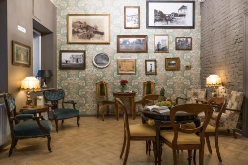Zimmer mit einem Tisch und Stühlen sowie einer Wand mit Bildern in der Unterkunft Metropolis Budapest Boutique Hotel in Budapest