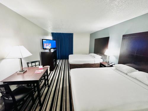 a hotel room with two beds and a desk and a television at Econo Lodge Ardmore in Ardmore