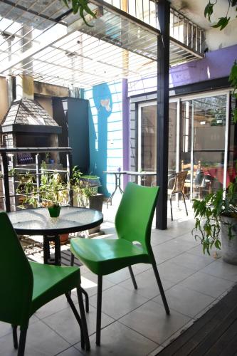patio con sillas verdes, mesa y fogones en Go Hostel en Córdoba