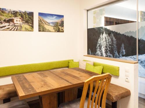 comedor con mesa de madera y cojines verdes en Apartment Sonnenhof-2 by Interhome, en Kaunertal