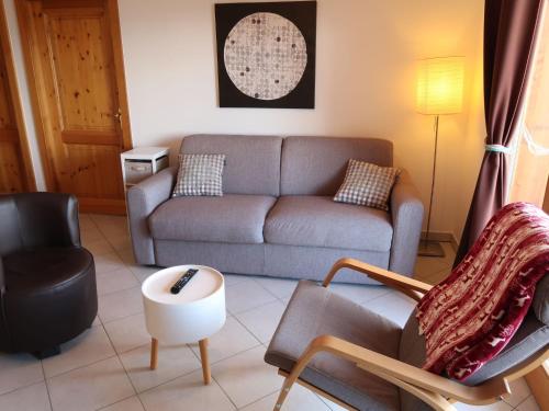 een woonkamer met een bank en een stoel bij Apartment Grand Panorama A5 by Interhome in Nendaz