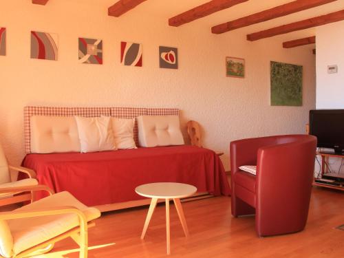 a bedroom with a red bed and a table and a chair at Apartment Le Bouquetin 5 by Interhome in Villars-sur-Ollon