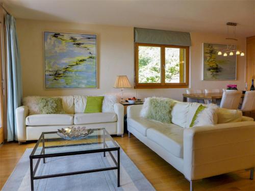 Apartment Orana by Interhome في كرانس مونتانا: غرفة معيشة مع كنبتين بيضاء وطاولة