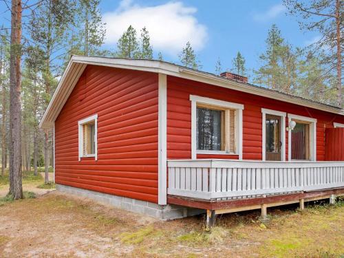 ein rotes Haus mit einer weißen Veranda im Wald in der Unterkunft Holiday Home Mäkitupa 2 by Interhome in Kuusamo