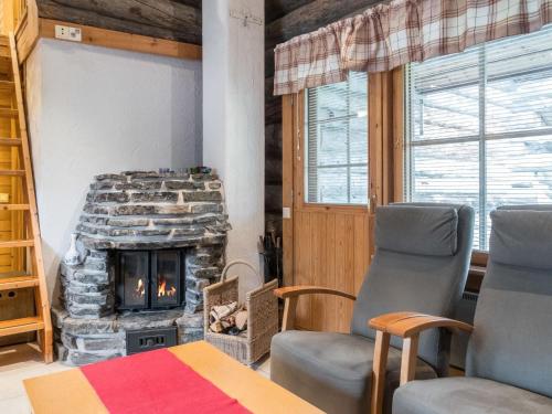 a living room with a stone fireplace and two chairs at Holiday Home Lauri 2 by Interhome in Sirkka