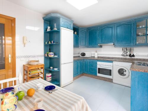 uma cozinha com armários azuis e um frigorífico branco em Holiday Home Villa Corales by Interhome em Torre de Benagalbón