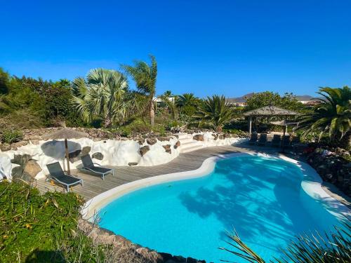 a swimming pool at a resort with chairs and trees at Villa La Laguna in Lajares